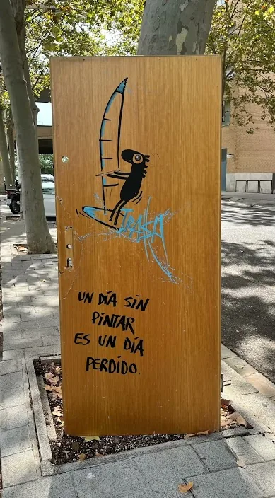Trædør med en malet figur og en linje om en dag uden at male, af Art Is Trash i Barcelona